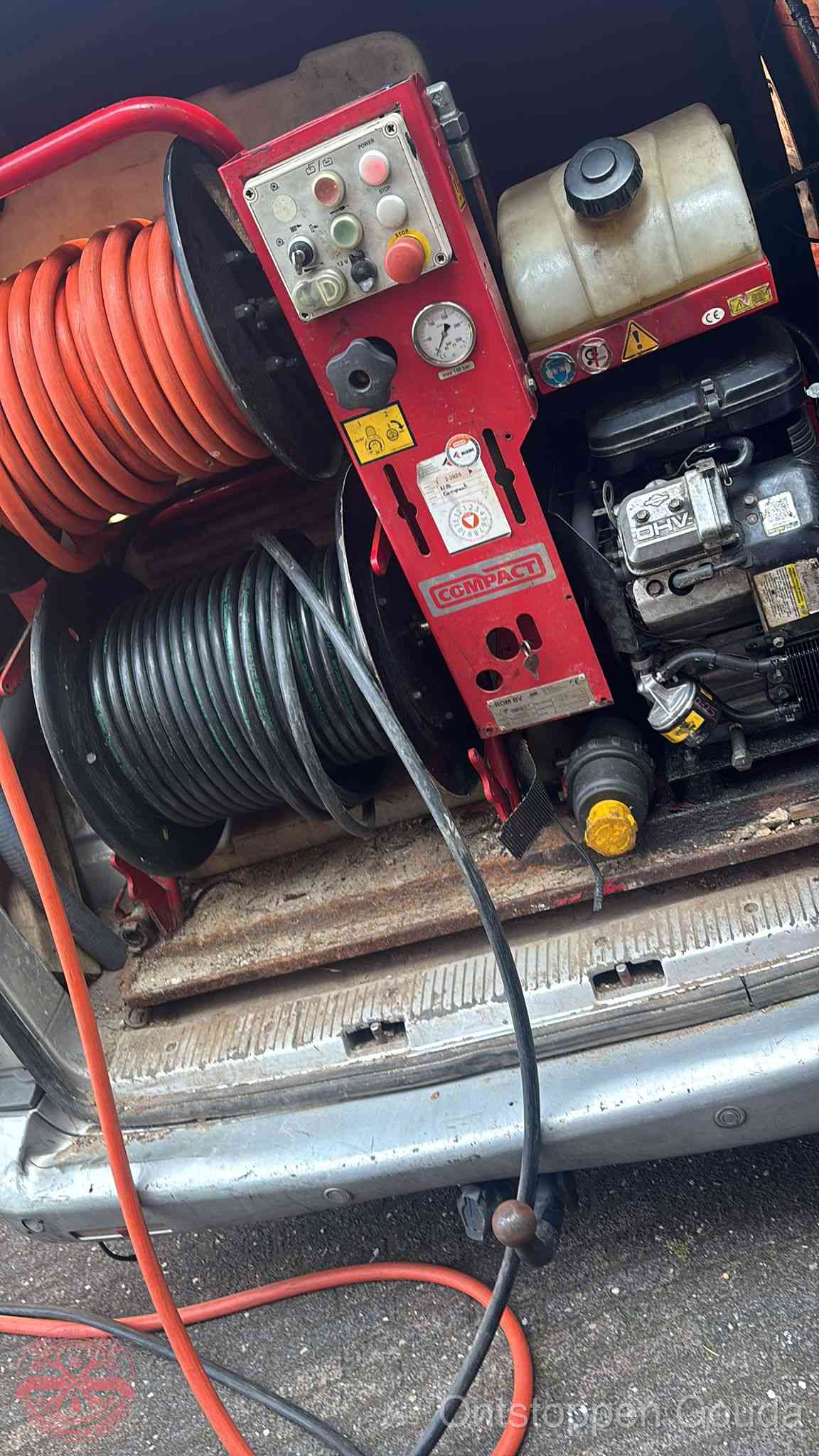 Een rood hogedruk-rioolreinigingstoestel met slangen in de laadbak van de bedrijfsbus, apparatuur voor een hardnekkige wc-verstopping in Gouda