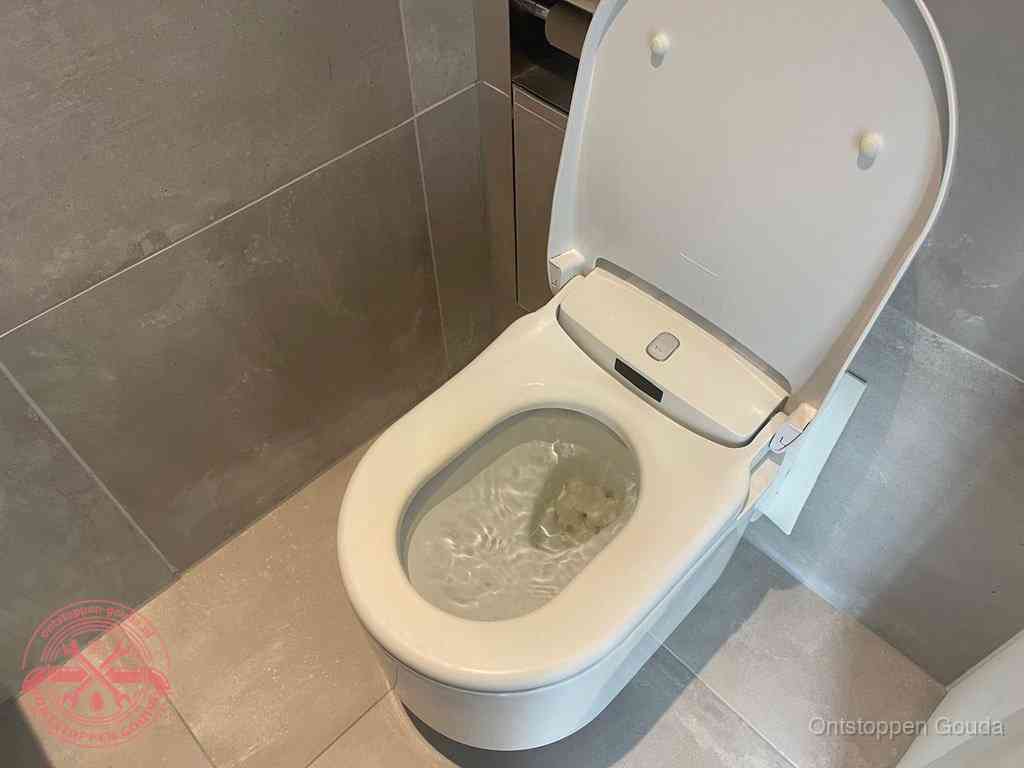 Een toiletpot vol troebel water met drijvend papier en restanten, de meest voorkomende oorzaak van een verstopte wc in Gouda