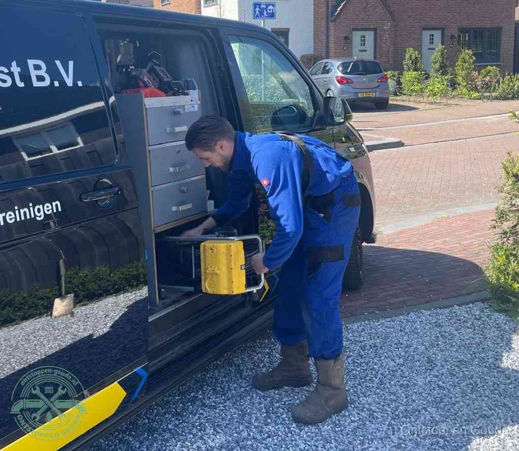 Een monteur pakt buiten op de oprit gereedschap uit de bedrijfsbus, het moment om een professional in te schakelen voor een verstopte afvoer in Gouda