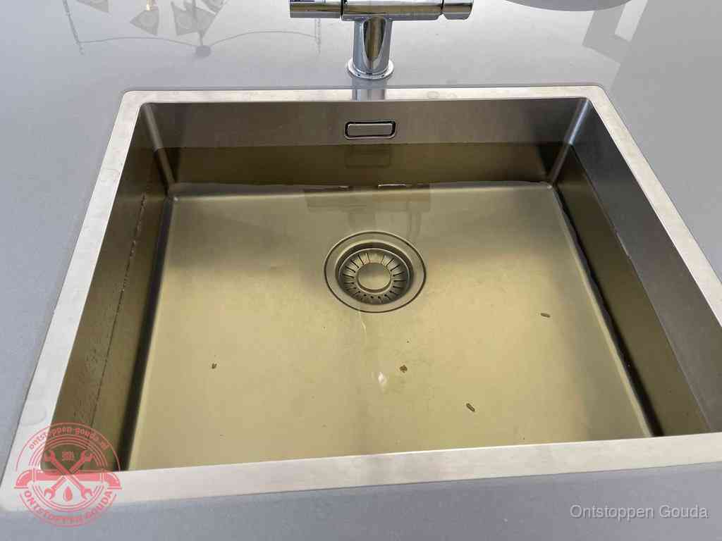 Stilstaand water in een rvs spoelbak dat niet wegloopt, een duidelijk signaal van een gootsteenverstopping in Gouda