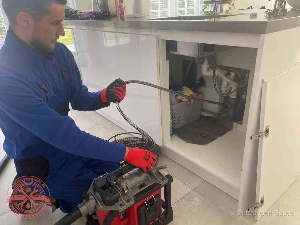 Een monteur reinigt de keukenafvoer grondig met een veermachine om terugkerende gootsteenverstoppingen te voorkomen in Gouda