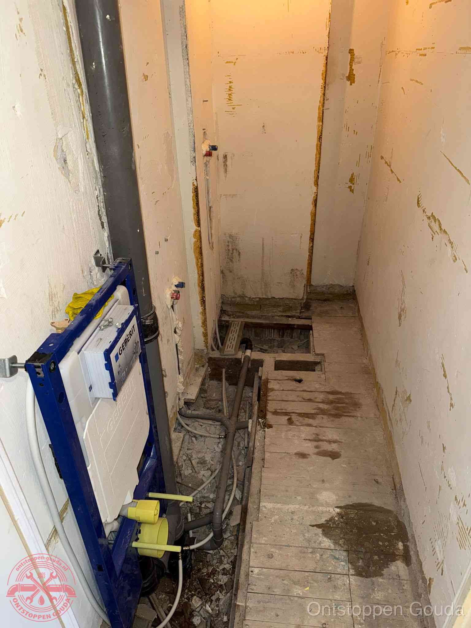 Een opgebroken toiletruimte tijdens renovatie met een Geberit inbouwreservoir en blootliggende oude afvoerleidingen, typisch voor oudere woningen in Gouda